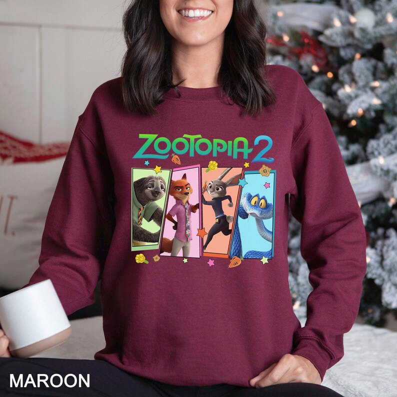 A woman wearing a burgundy sweatshirt with a colorful graphic of the characters from the animated film "Zootopia 2".