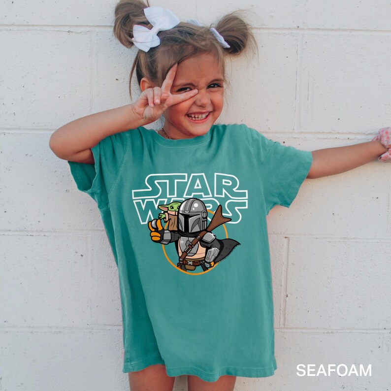 a little girl wearing a star wars t - shirt