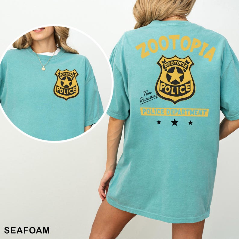 A woman wearing a light blue t-shirt with a police badge and text on the back.