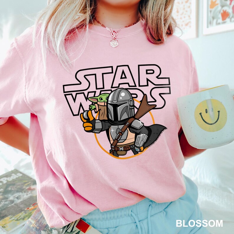 a woman wearing a pink star wars shirt holding a coffee mug