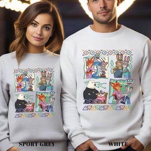 Two people wearing white sweatshirts with a colorful graphic of cartoon animals and characters on them.