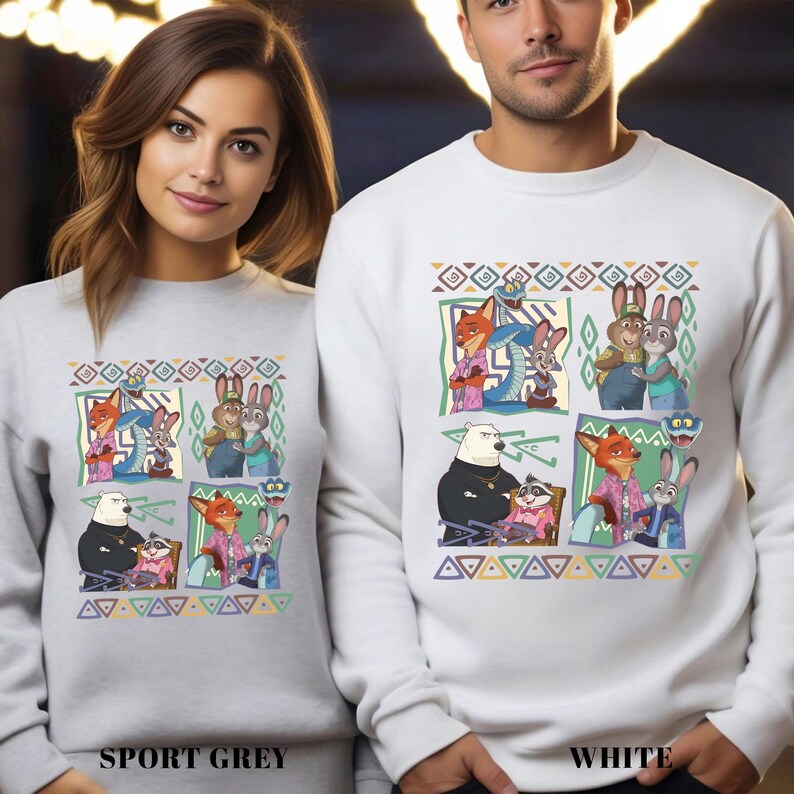 Two people wearing white sweatshirts with a colorful graphic of cartoon animals and characters on them.