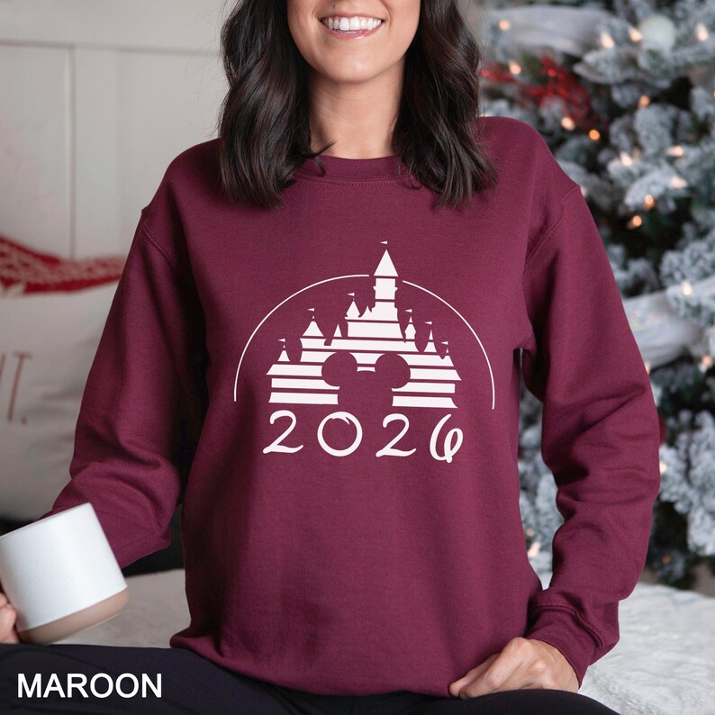 A woman wearing a burgundy sweater with a white graphic design of a castle and the year "2020" printed on it.