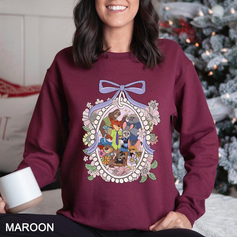 A woman wearing a burgundy sweater with a colorful graphic design featuring various cartoon characters and floral elements.