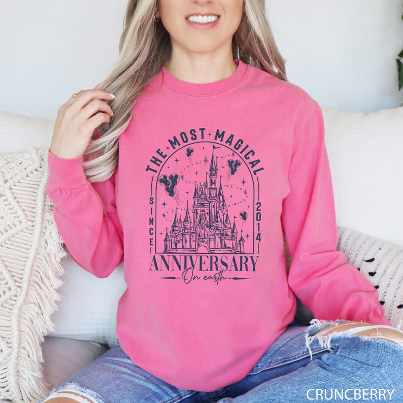 a woman sitting on a couch wearing a pink sweatshirt