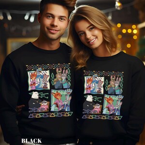 A man and a woman are standing next to each other, both wearing black sweatshirts with colorful cartoon animal characters printed on them.