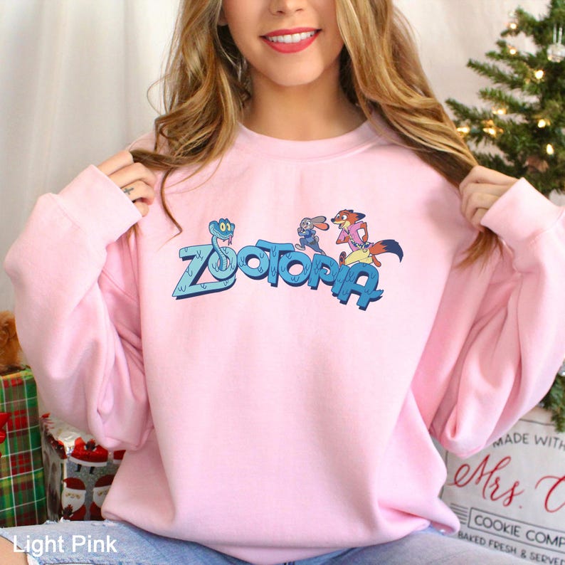 A woman wearing a pink sweatshirt with the word "Zootopia" printed on it.
