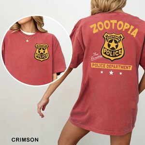 A red t-shirt with a police department logo and text, including the words "Zootopia Police Department" and "The New Recruiting Police Department".