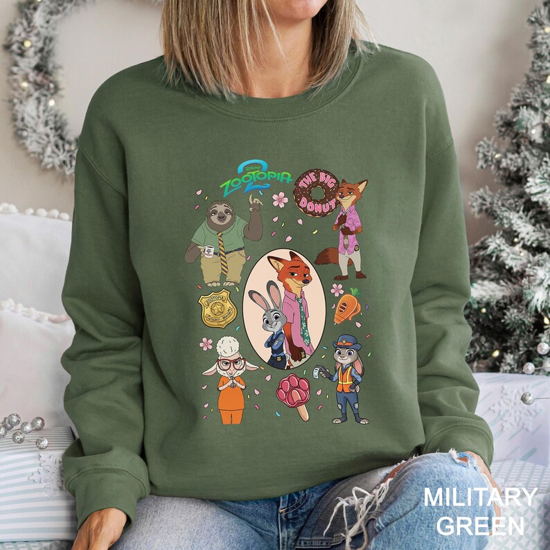 A woman wearing a green sweatshirt with a graphic design featuring various cartoon characters from the movie "Zootopia".