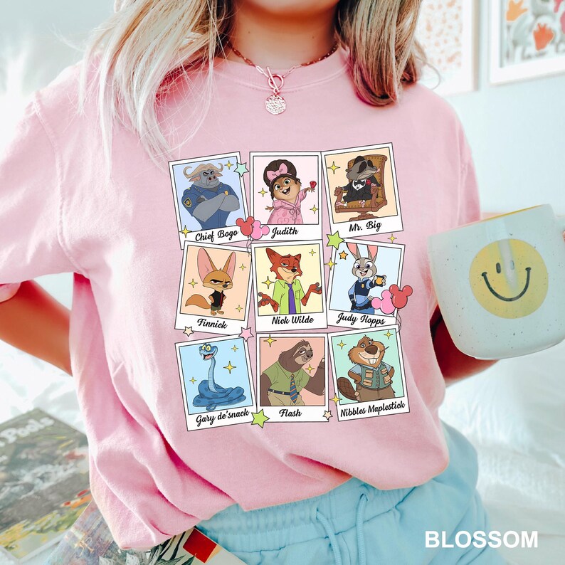 A woman wearing a pink t-shirt with a graphic of cartoon characters and a mug with a smiley face.