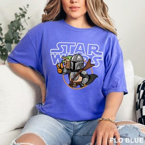 a woman sitting on a couch wearing a star wars t - shirt