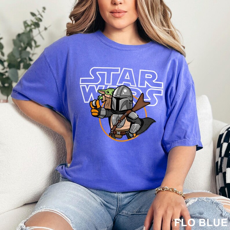 a woman sitting on a couch wearing a star wars t - shirt
