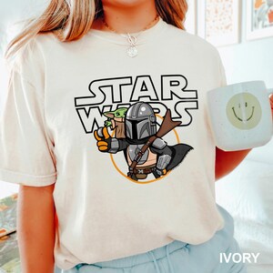 a woman wearing a star wars t - shirt holding a mug