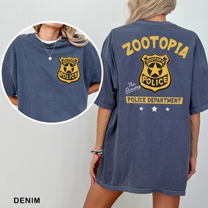 a person wearing a blue t-shirt with a yellow police badge and text on the back.