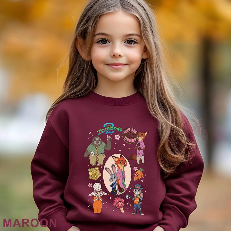 A young girl wearing a maroon sweater with a colorful graphic of cartoon characters from the animated film "The Big Lebowski".