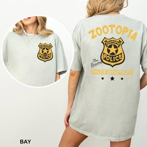 A woman wearing a grey t-shirt with a police department logo and text on the back.