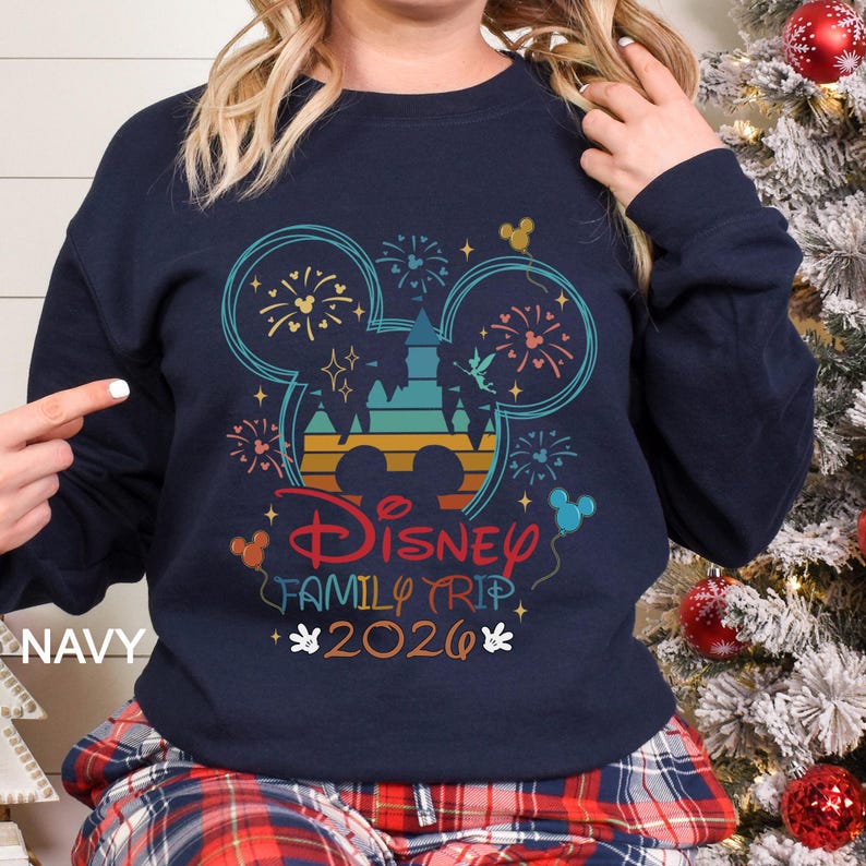 A woman wearing a navy blue sweatshirt with a Disney-themed graphic and text, including a Mickey Mouse design and fireworks.