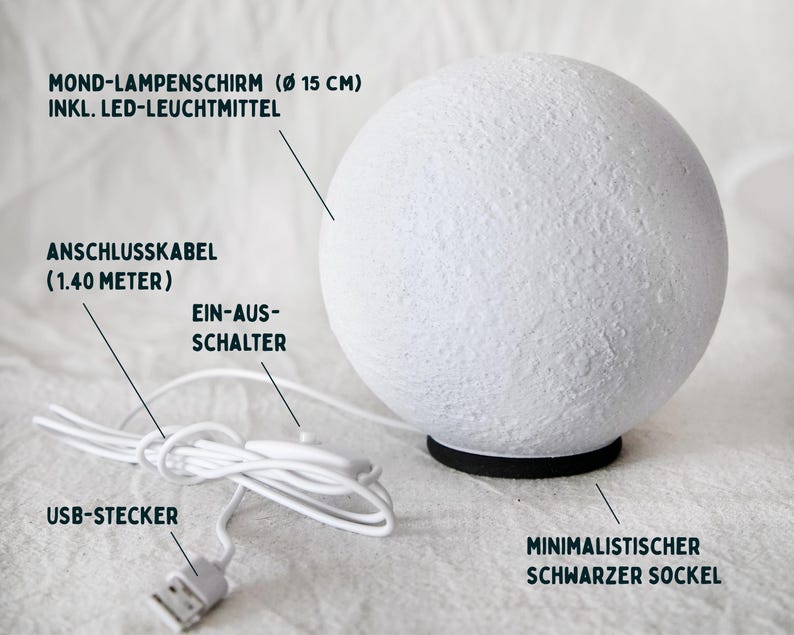 May include: A white, spherical lamp with a textured surface, resting on a black base. The lamp has a USB connector and a 1.40-meter cable. The text on the image says: "Moon lampshade (&Oslash; 15 cm) incl. LED light source".