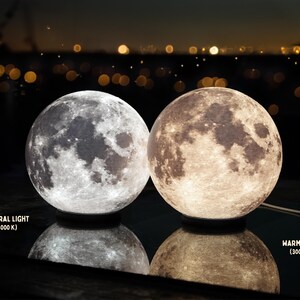 May include: Two spherical moon lamps, one with neutral light (4000 K) and the other with warm light (3000 K). The lamps are on a reflective surface, with the text "NEUTRAL LIGHT" and "WARM LIGHT" visible.