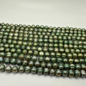 May include: A strand of green freshwater pearls with a slight iridescent sheen. The pearls are round and have a smooth surface.
