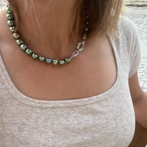 May include: A green pearl necklace with a silver clasp. The necklace is made of large, round pearls.