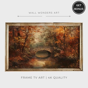 May include: A framed painting of a stone bridge over a stream in a forest. The trees have autumn leaves in shades of red, orange, and yellow. The painting is in a silver frame. "WALL WONDERS ART" and "FRAME TV ART | 4K QUALITY" are printed below the image.