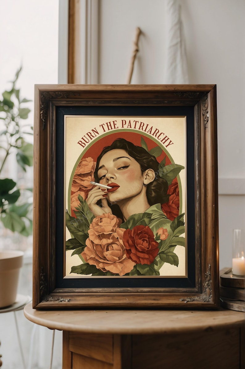 K&ouml;nnte beinhalten: Ein gerahmter Druck mit Vintage-&Auml;sthetik, der eine Frau mit dunklen Haaren und roten Lippen zeigt, die eine Zigarette raucht. Sie ist umgeben von roten und pfirsichfarbenen Rosen und gr&uuml;nen Bl&auml;ttern. Der Text "BURN THE PATRIARCHY" ist in rot und gr&uuml;n um den Kopf der Frau geschrieben.