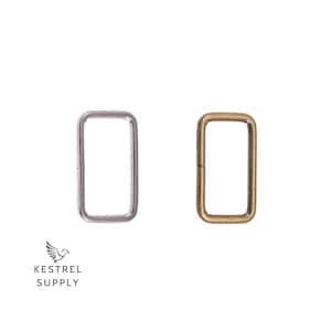 May include: Two metal rectangular rings, one silver and one gold, for attaching to a strap or belt.