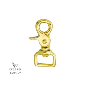 Puede incluir: Un mosquetón giratorio de metal dorado con un bucle rectangular. El mosquetón está diseñado para sujetarse a correas, correas o otros artículos.