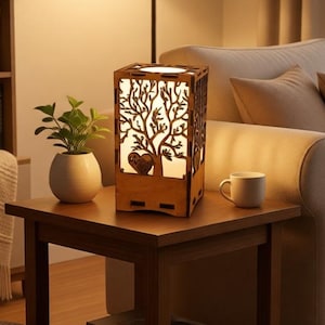 May include: A wooden table lamp with a tree design, illuminated from within. The lamp is on a dark brown side table, next to a white mug and a small potted plant. The room has a warm, inviting atmosphere.