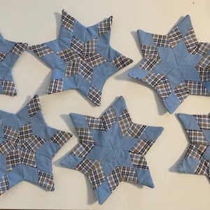 Könnte beinhalten: Sechs sternförmige, gequiltete Untersetzer aus blauem und braunem kariertem Stoff.