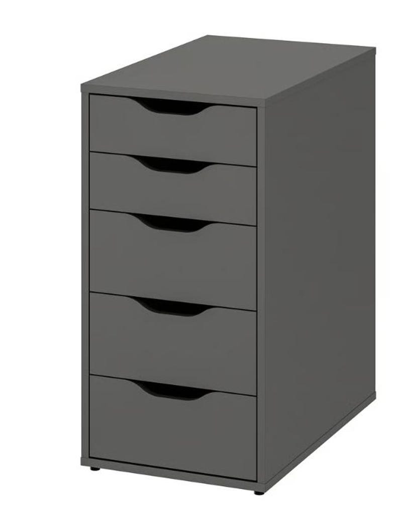 May include: A dark gray storage unit featuring five stacked drawers. Each drawer is equipped with a semi-circular cutout handle located at the top center. The unit has a rectangular frame with a flat top surface and sits on small, low-profile feet.