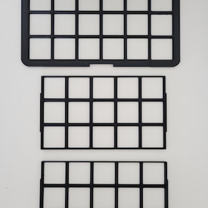 May include: Three black rectangular grid organizers with a uniform square pattern. The top piece features a solid outer frame with rounded corners, while the two lower pieces consist of thin, open-frame dividers with small side tabs for assembly.