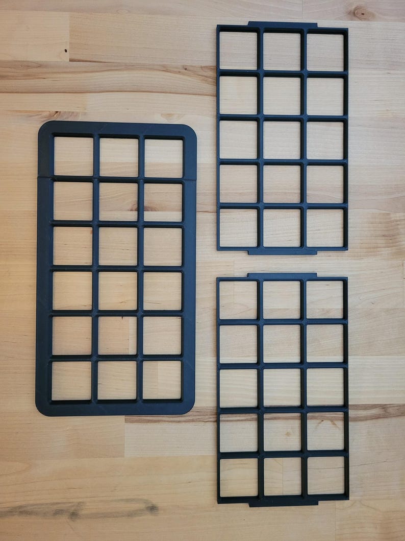 May include: Three black rectangular grid organizers with a uniform square pattern. One large grid is positioned on the left, while two smaller, identical grid inserts are stacked vertically on the right side, all featuring a matte finish.