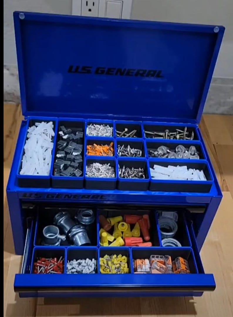 May include: A blue U.S. General metal tool chest with an open lid and one extended drawer. The interior contains multiple black plastic bins filled with various hardware, including screws, wall anchors, wire connectors, and metal fittings.