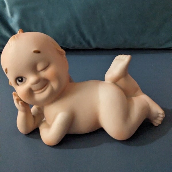 Vintage Kewpie figurine, laying down with a wink and tiny blue wings