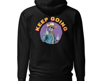 Könnte beinhalten: Schwarzer Kapuzenpullover mit einer Grafik eines Skeletts mit Cowboyhut und Jeansjacke, das einen Daumen hoch gibt. Der Text "KEEP GOING" ist in Gelb und Rosa über dem Skelett angeordnet. Das Design ist auf der Rückseite des Kapuzenpullovers zentriert.