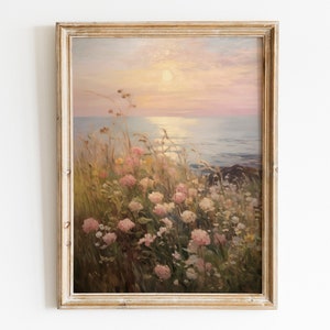 May include: A framed painting depicting a seascape with a pink and purple sunset over the ocean. The foreground features a field of pink and white flowers.