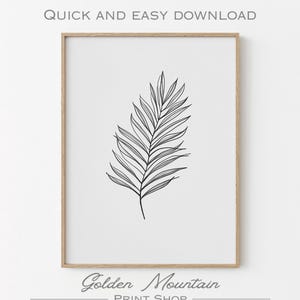 Puede incluir: Una impresión enmarcada con un dibujo lineal en blanco y negro de una hoja de palma. La obra de arte está sobre un fondo blanco y enmarcada en un marco de madera marrón claro. También se ve el texto "QUICK AND EASY DOWNLOAD" y "Golden Mountain PRINT SHOP".
