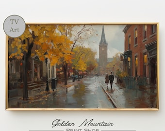 Könnte beinhalten: Ein gerahmter Druck einer herbstlichen Straßenszene. Das Kunstwerk zeigt eine nasse Straße mit goldenen Bäumen, Backsteingebäuden und einem Kirchturm im Hintergrund. Zwei Personen gehen die Straße entlang. Der Druck ist mit "TV Art" und "Golden Mountain PRINT SHOP" beschriftet.