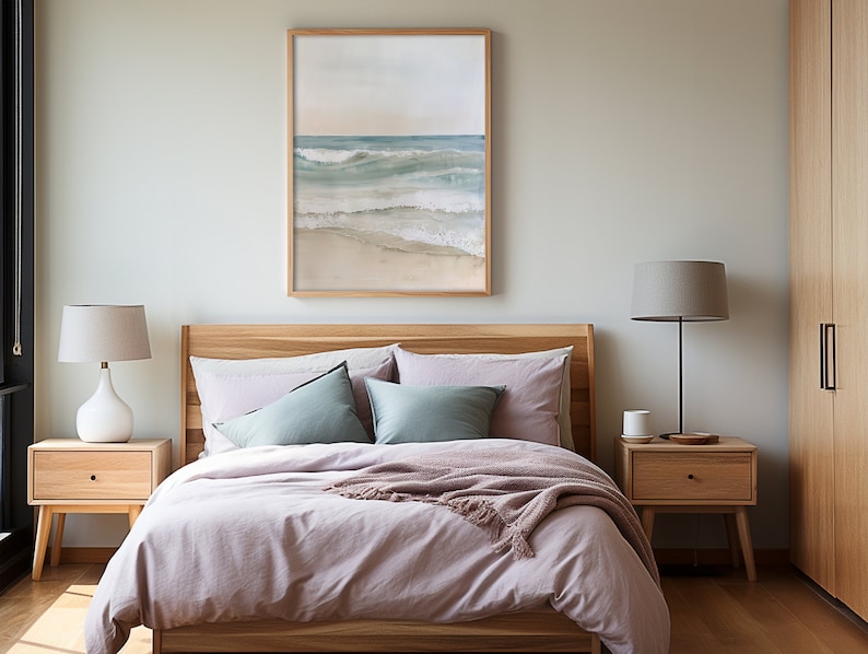 K&ouml;nnte beinhalten: Ein Schlafzimmer mit einem hellrosa Bettbezug und einem Holzbettgestell. &Uuml;ber dem Bett h&auml;ngt ein gerahmtes Bild mit einer Strandszene, und es gibt zwei Nachttische mit Lampen.