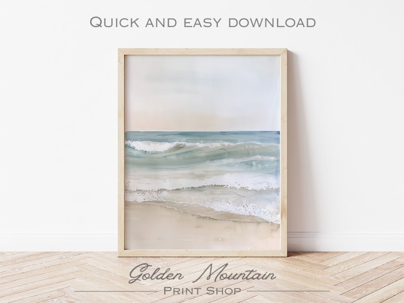 K&ouml;nnte beinhalten: Ein Aquarellbild von Ozeanwellen, die an einem Sandstrand brechen. Das Bild ist in einem hellen Holzrahmen gerahmt und h&auml;ngt an einer wei&szlig;en Wand.