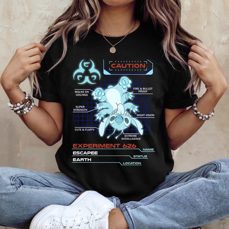 May include: Black t-shirt featuring a blue graphic of Experiment 626, with the text "CAUTION" and various attributes like "Fire & Bullet Proof" and "Extreme Intelligence." The shirt also includes the text "Experiment 626" and "Escapee."