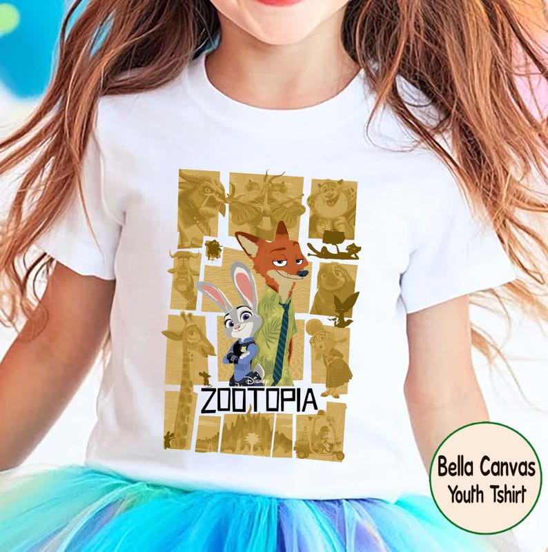 May include: White youth t-shirt featuring characters from the Disney movie Zootopia. The design includes Nick Wilde, Judy Hopps, and other characters in a gold-toned collage. The word "ZOOTOPIA" is printed in black. The shirt is a Bella Canvas youth t-shirt.