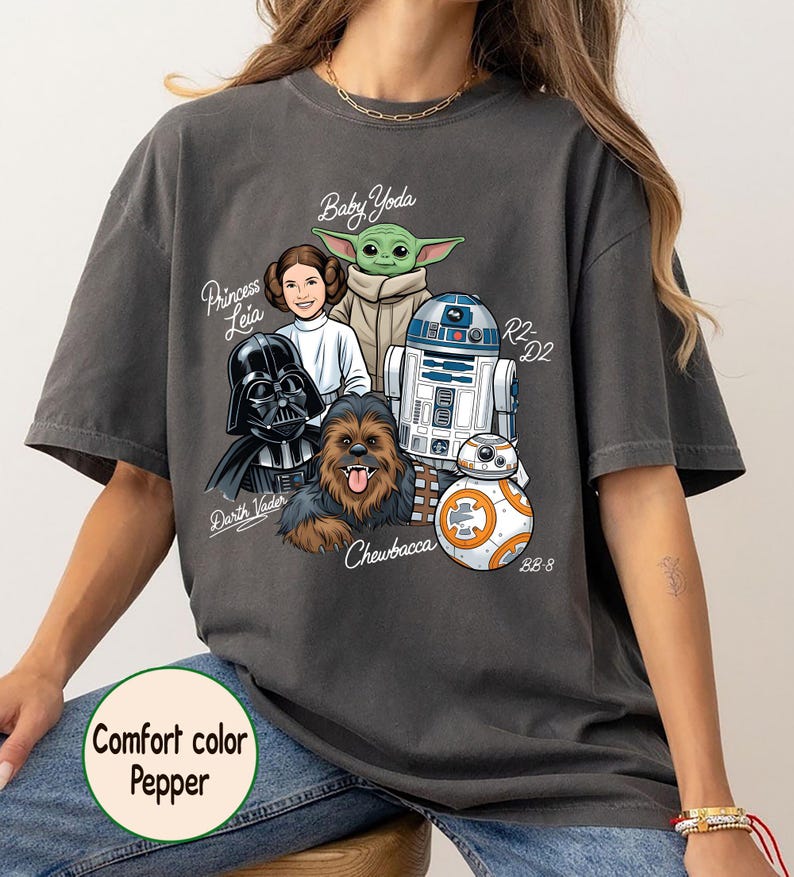May include: Dark grey t-shirt featuring Star Wars characters: Darth Vader, Princess Leia, Baby Yoda, Chewbacca, R2-D2, and BB-8. The shirt has the text "Comfort color Pepper".