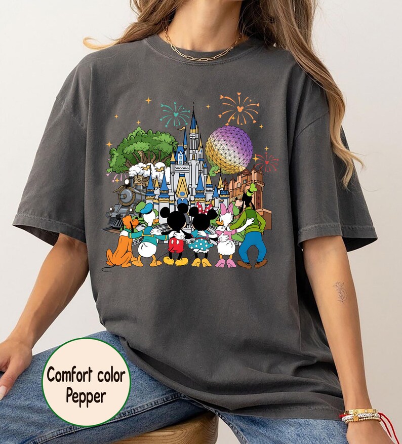 Peut inclure: T-shirt gris fonc&eacute; Comfort Colors avec un motif color&eacute; de personnages Disney devant un ch&acirc;teau, une grande sph&egrave;re et des feux d'artifice. Le texte "Comfort color Pepper" est imprim&eacute; sur le t-shirt.