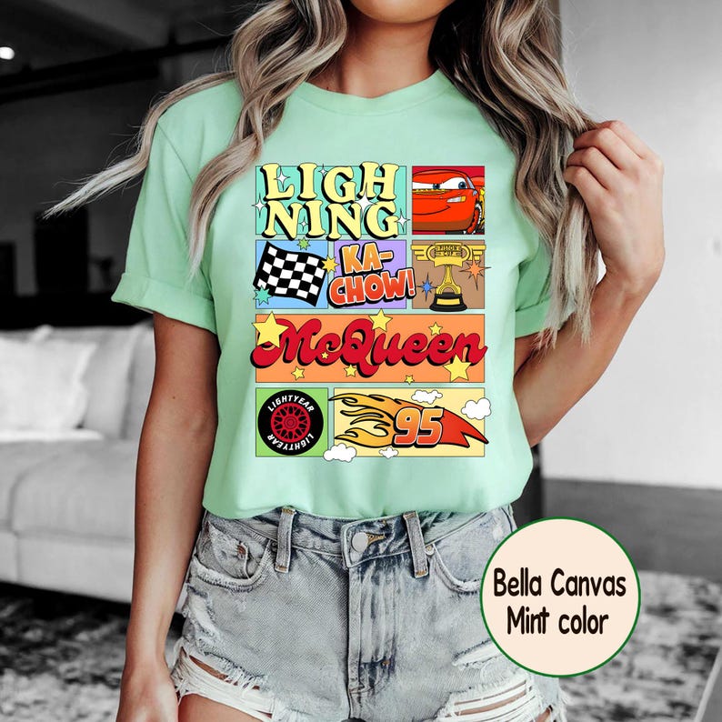 Puede incluir: Camiseta verde menta con un dise&ntilde;o gr&aacute;fico colorido. El dise&ntilde;o incluye el texto "LIGHTNING KA-CHOW! McQueen" junto con im&aacute;genes de un coche de carreras, una bandera a cuadros y el n&uacute;mero 95. Fabricada en Bella Canvas.