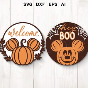 May include: Two circular Halloween signs. One has a pumpkin design with the word "welcome". The other sign features a Mickey Mouse-inspired pumpkin design with the words "hey BOO" and spiderwebs. The signs are brown, orange, and white.
