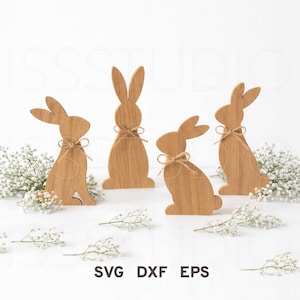 Könnte beinhalten: Vier Holzhasenfiguren mit Bindfäden, angeordnet mit weißem Schleierkraut. Die Hasen sind in verschiedenen Posen, mit dem Text "SVG DXF EPS" unten. Eine charmante Oster- oder Frühlingsdekoration.