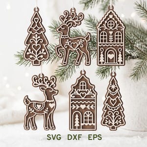 May include: Six dark brown wooden hanging ornaments featuring laser-cut white outlines of two reindeer, two Christmas trees, and two houses with heart motifs. The text SVG DXF EPS is printed at the bottom of the image in dark green letters.